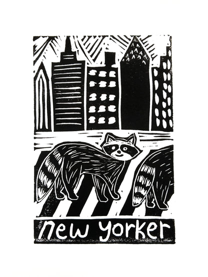 Print of two raccoons crossing a street with city skyline in the background, with 'new yorker' text.