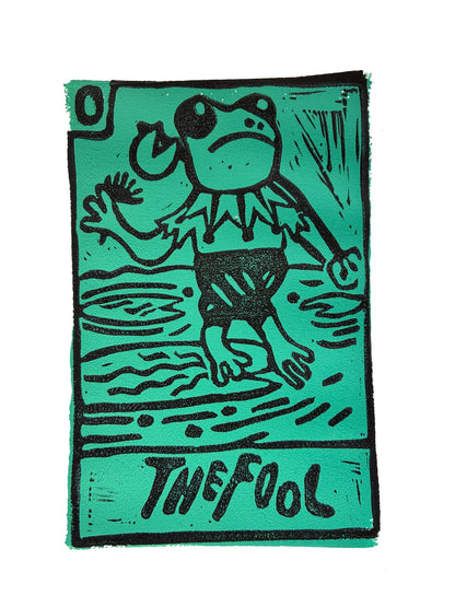 Green and black Tarot card print with a stylized frog dressed as a jester and 'The Fool' text.