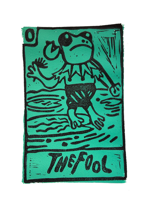 Green and black Tarot card print with a stylized frog dressed as a jester and 'The Fool' text.