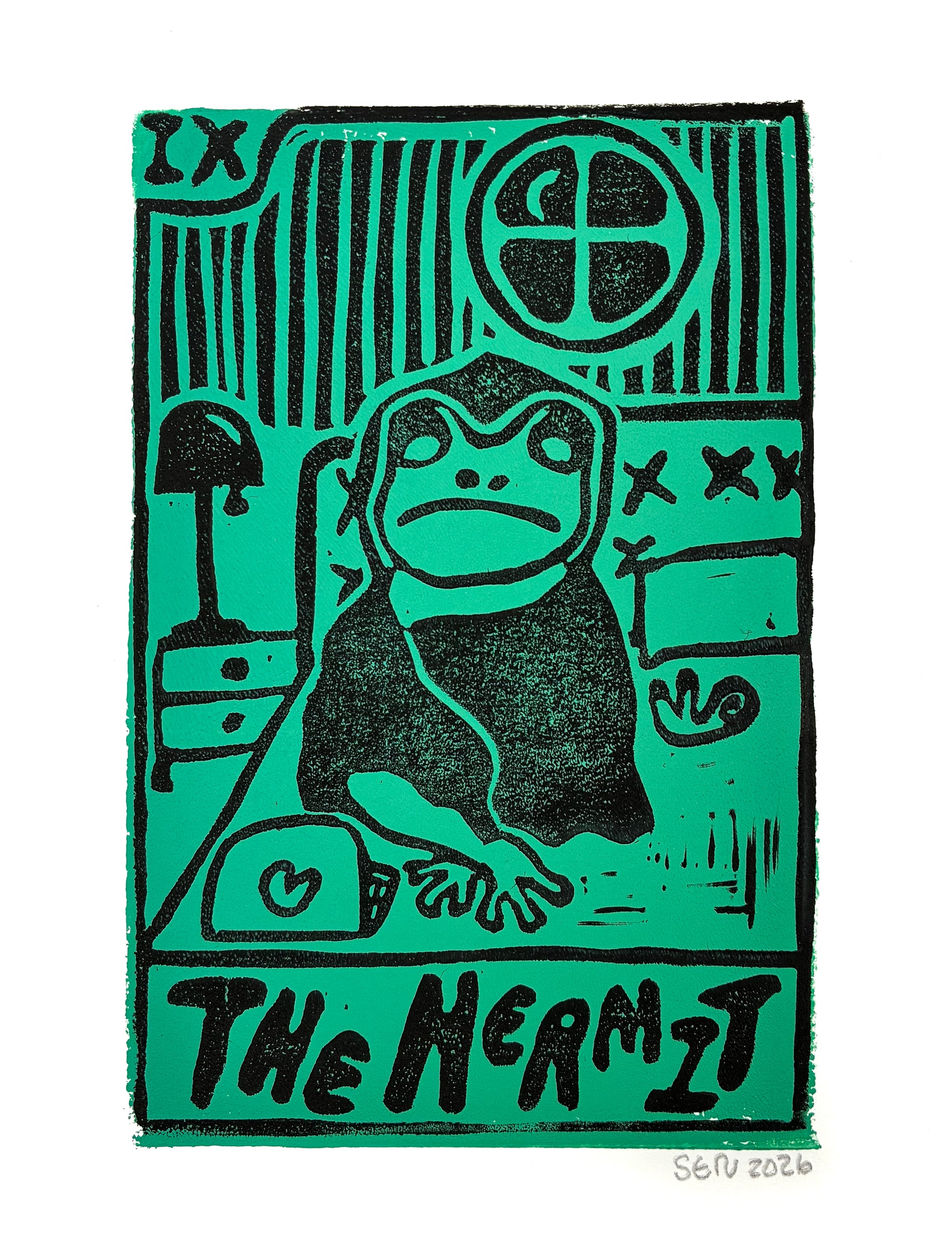 A square art print featuring a stylized black ink illustration of a hermit frog on a bright green background, with the text 'THE HERMIT' at the bottom and an artist signature 'SOU 2026' in the lower right corner.