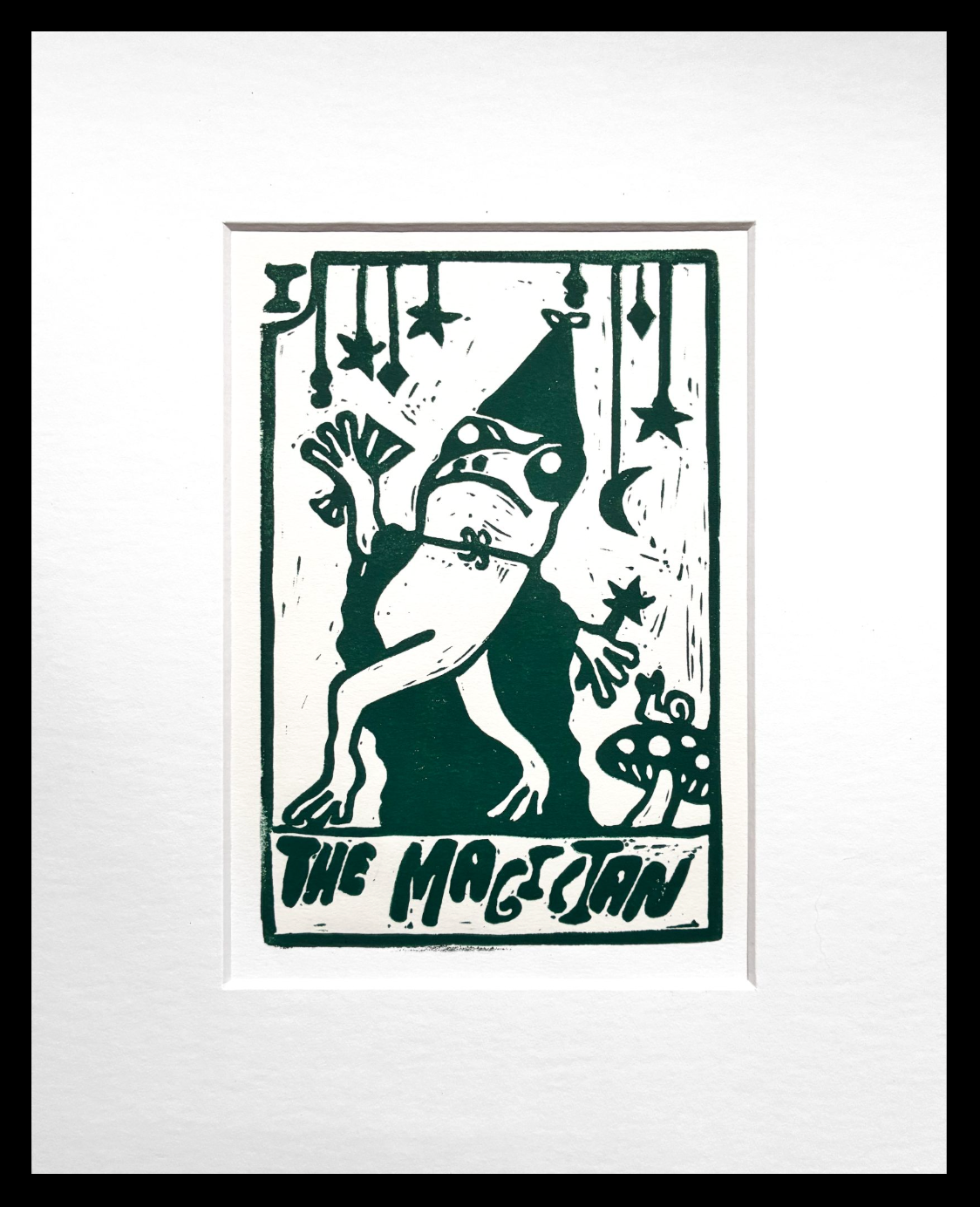 Green and white print of frog dressed as a magician, matted