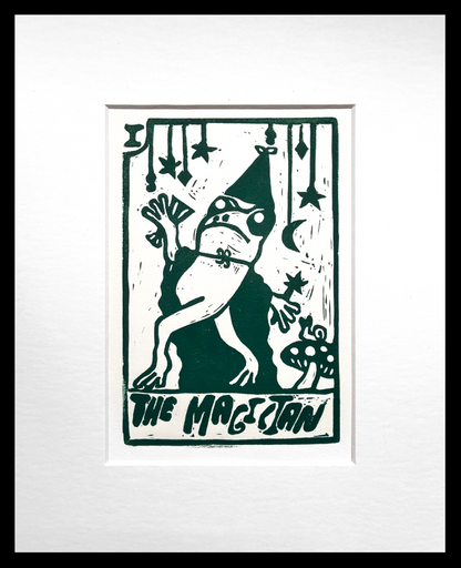 Green and white print of frog dressed as a magician, matted